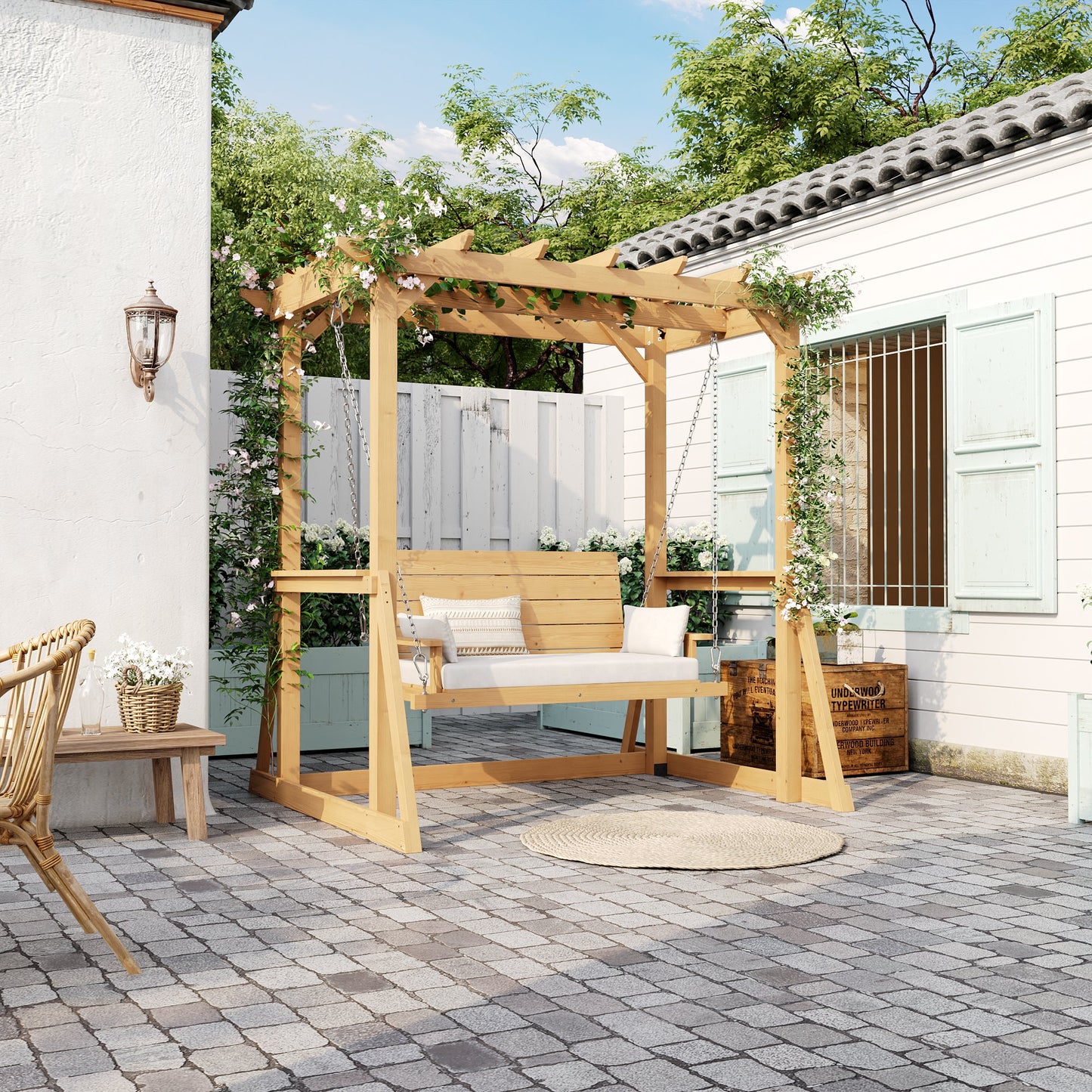 Wooden pergola with a swing on a patio area with a white building and greenery in the background