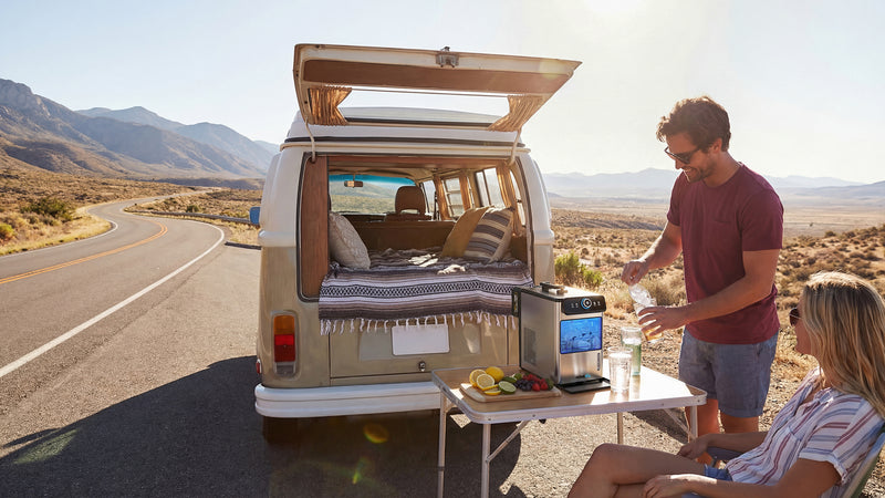 Two people enjoying a picnic by a camper van in a desert setting.