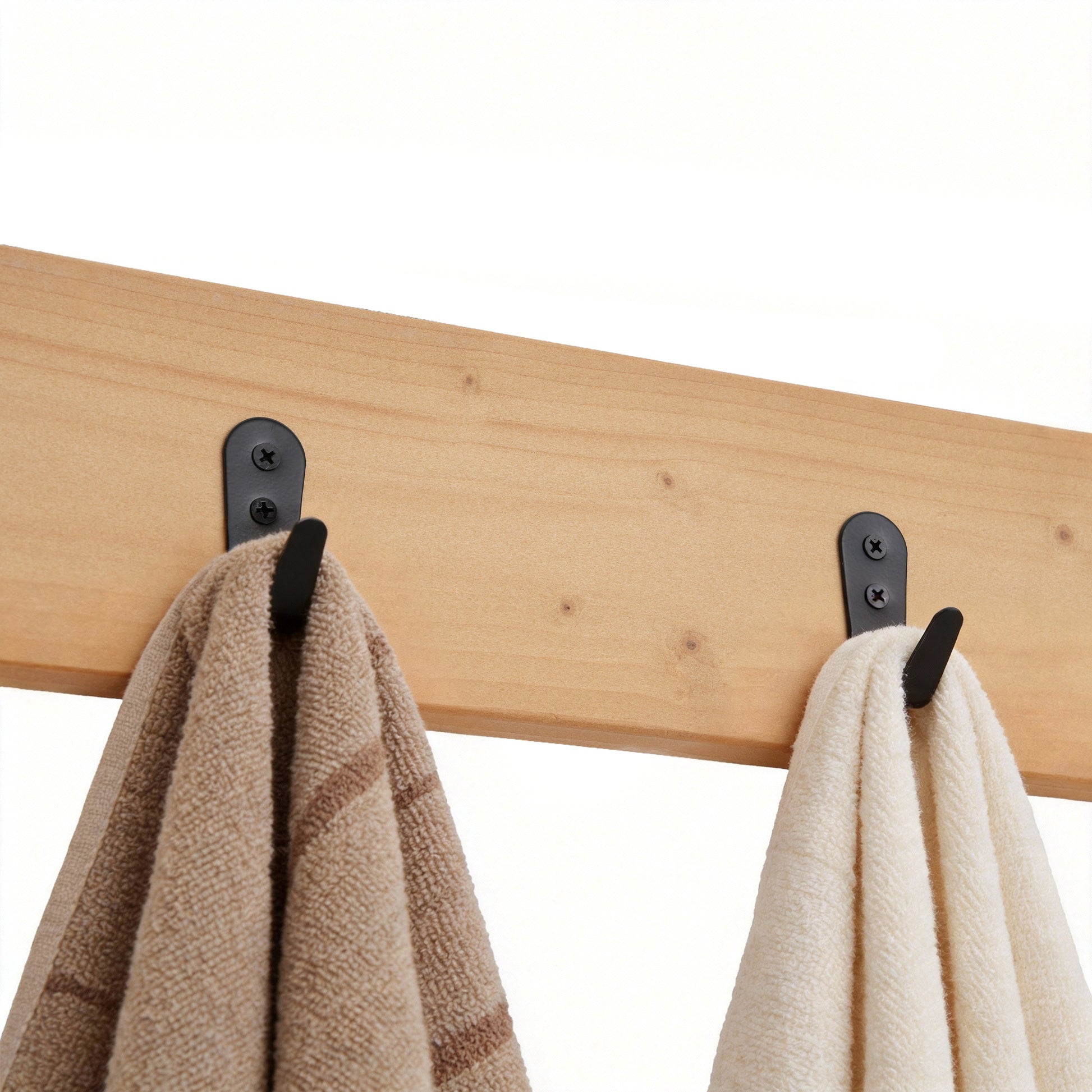 Wooden rack with black hooks holding two towels on a white background